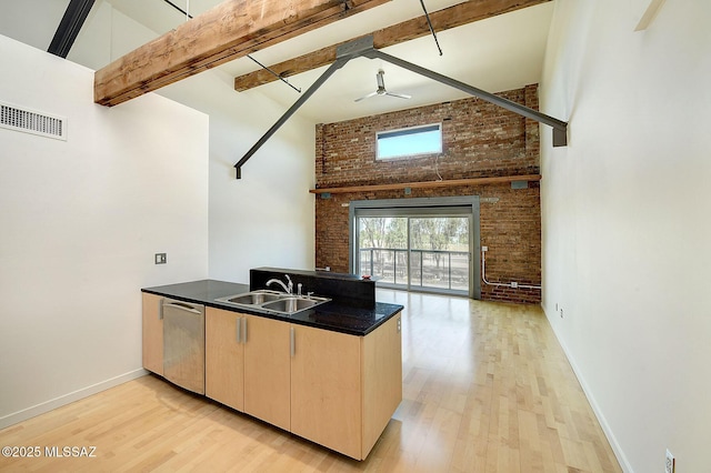 kitchen featuring ceiling fan, dishwasher, sink, beamed ceiling, and brick wall