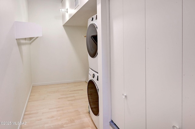 laundry area with light wood-type flooring and stacked washer / dryer