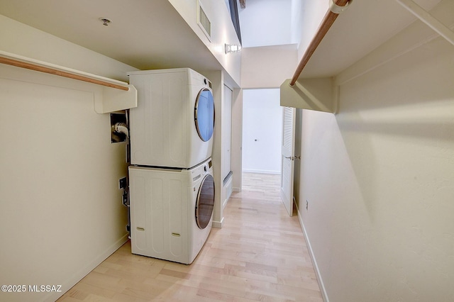 clothes washing area featuring stacked washer and dryer and light hardwood / wood-style floors