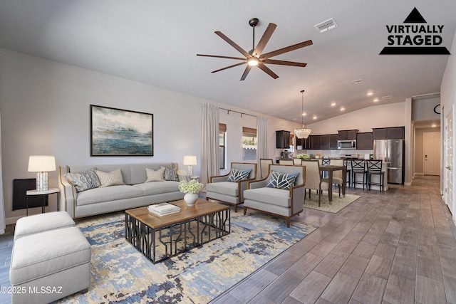 living room featuring lofted ceiling and ceiling fan with notable chandelier