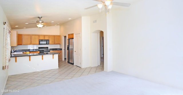 kitchen with a breakfast bar, black appliances, ceiling fan, light tile patterned floors, and kitchen peninsula