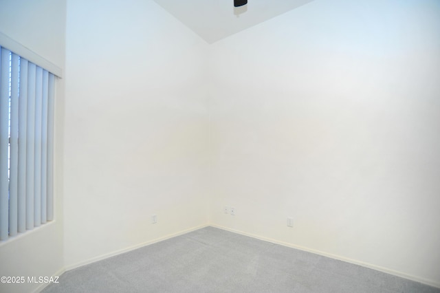 carpeted empty room with vaulted ceiling