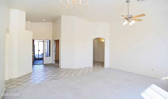 unfurnished room featuring ceiling fan with notable chandelier, light tile patterned floors, and a high ceiling