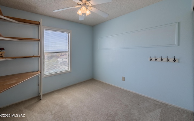 unfurnished room featuring light carpet, a textured ceiling, and a ceiling fan