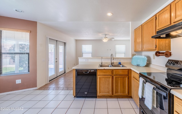 kitchen with a peninsula, black appliances, under cabinet range hood, light countertops, and a sink