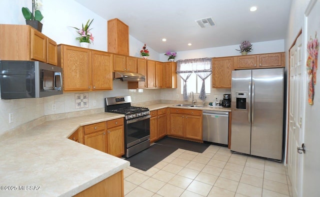 kitchen with vaulted ceiling, decorative backsplash, appliances with stainless steel finishes, light tile patterned flooring, and sink