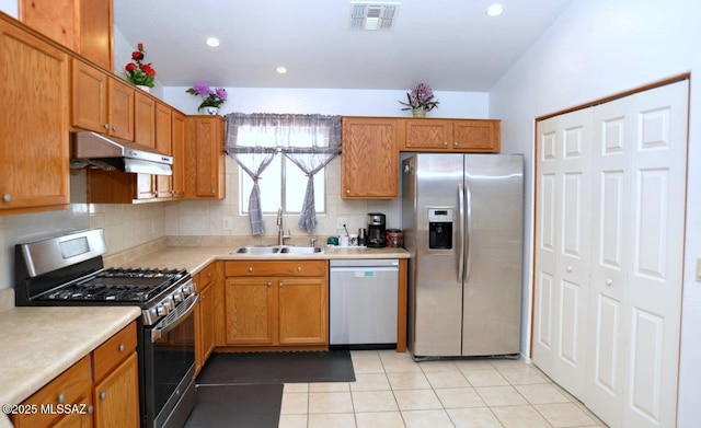 kitchen with appliances with stainless steel finishes, decorative backsplash, light tile patterned flooring, and sink