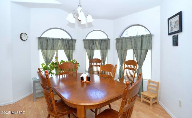 dining space with light hardwood / wood-style flooring and a chandelier