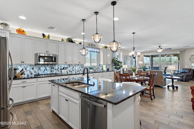 kitchen featuring stainless steel appliances, sink, ceiling fan, a center island with sink, and pendant lighting