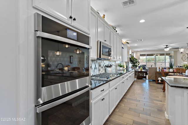 kitchen with white cabinets, ceiling fan, decorative backsplash, pendant lighting, and appliances with stainless steel finishes