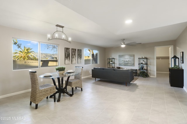 tiled dining room featuring ceiling fan with notable chandelier