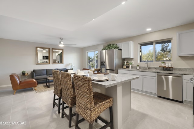 kitchen featuring a breakfast bar, white cabinetry, appliances with stainless steel finishes, ceiling fan, and sink