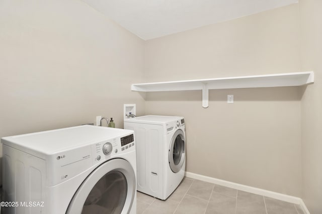 laundry area with washer and clothes dryer and light tile patterned floors