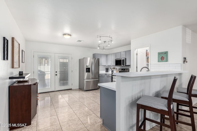 kitchen with french doors, a breakfast bar, gray cabinets, kitchen peninsula, and stainless steel appliances