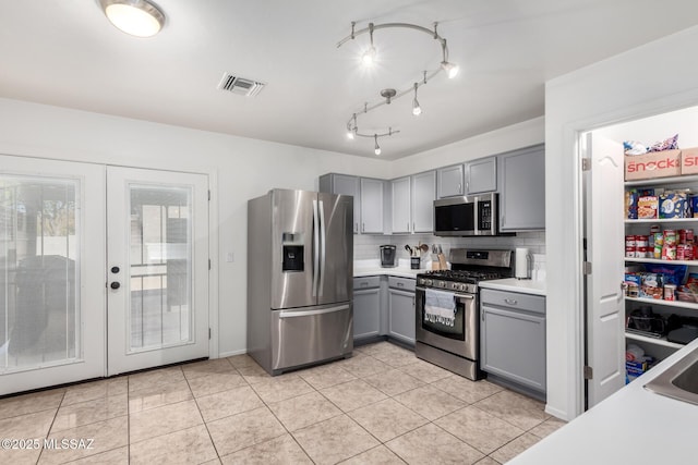 kitchen featuring french doors, appliances with stainless steel finishes, decorative backsplash, and gray cabinetry