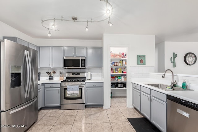 kitchen featuring sink, gray cabinetry, light tile patterned floors, stainless steel appliances, and decorative backsplash