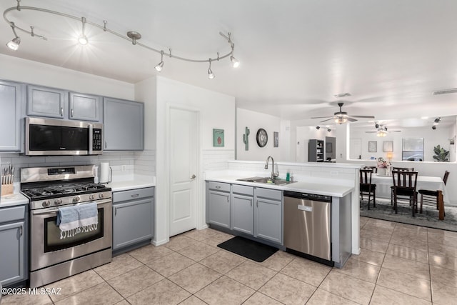 kitchen featuring stainless steel appliances, kitchen peninsula, sink, and gray cabinetry