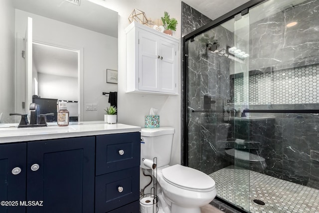 bathroom featuring toilet, vanity, and a shower with shower door