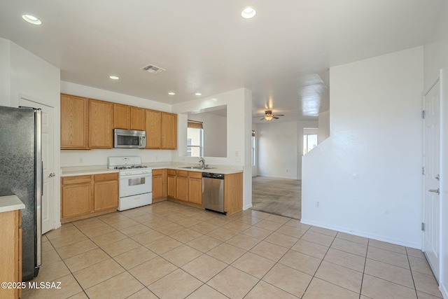 kitchen with a healthy amount of sunlight, light tile patterned floors, appliances with stainless steel finishes, and a sink