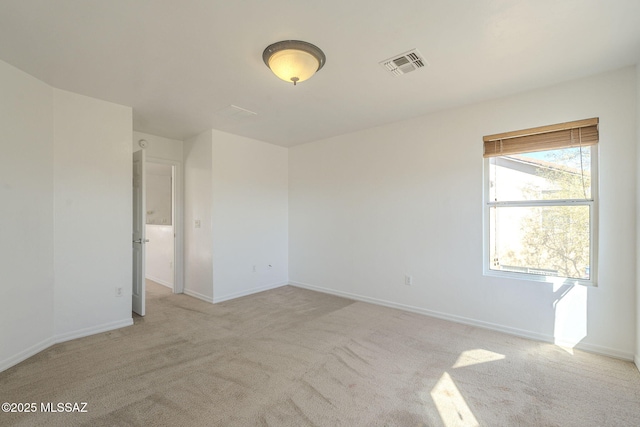 spare room with baseboards, visible vents, and light colored carpet