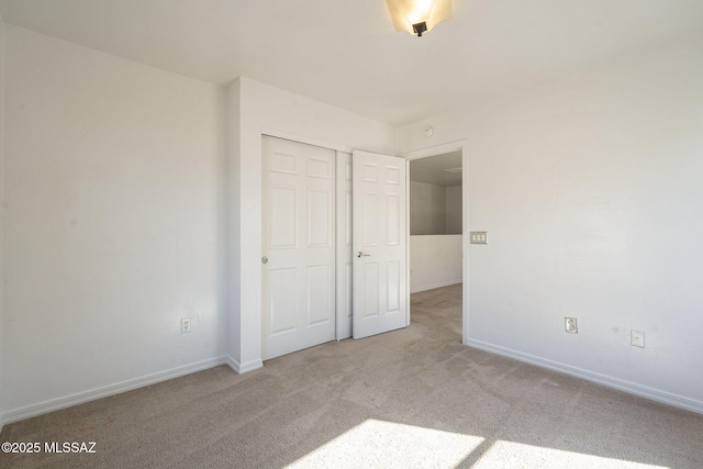 unfurnished bedroom with a closet, carpet flooring, and baseboards