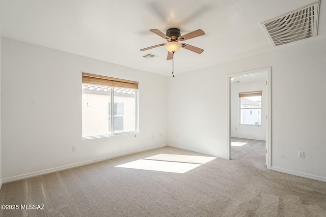 carpeted spare room with baseboards, visible vents, and a wealth of natural light