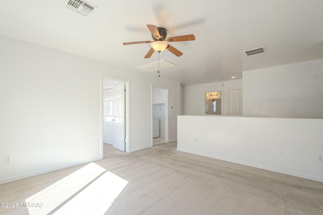 empty room featuring light carpet, visible vents, baseboards, a ceiling fan, and washer / clothes dryer