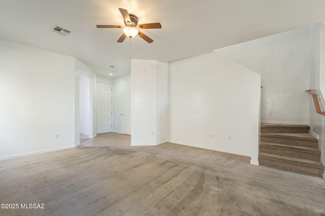 unfurnished living room with light colored carpet, visible vents, stairway, a ceiling fan, and baseboards