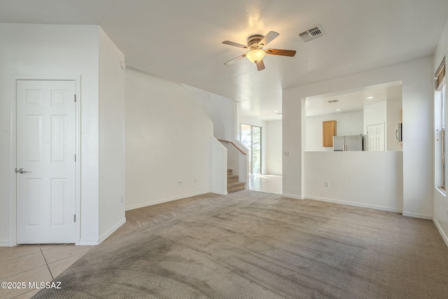 unfurnished living room with light tile patterned floors, light carpet, visible vents, baseboards, and stairs