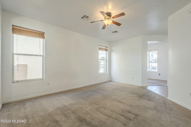 spare room with light carpet, ceiling fan, visible vents, and baseboards