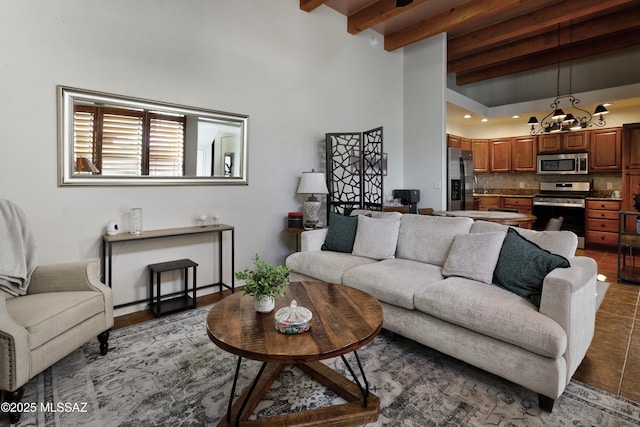 living room with a notable chandelier, dark tile patterned floors, and beamed ceiling