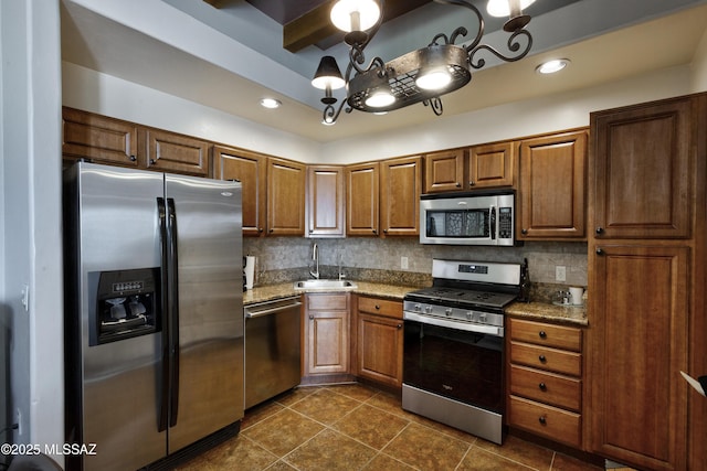kitchen featuring stainless steel appliances, decorative backsplash, dark stone countertops, and sink