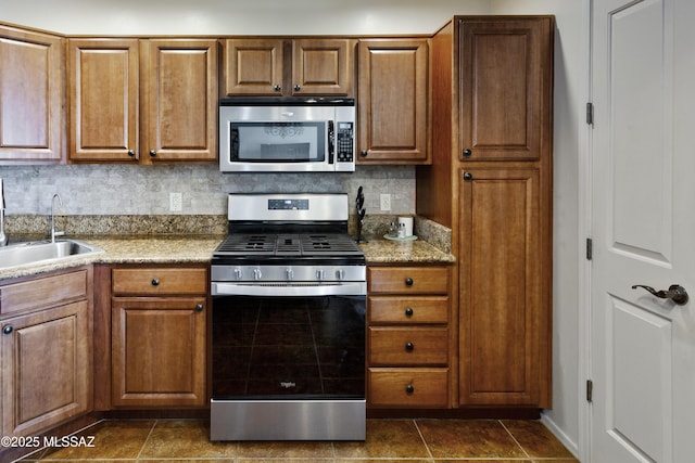 kitchen with light stone counters, sink, backsplash, and appliances with stainless steel finishes