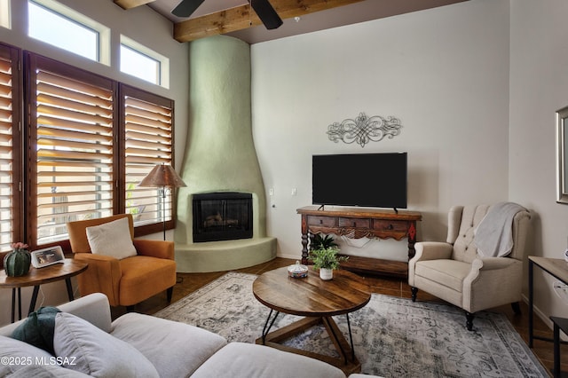 living room with a fireplace, ceiling fan, beam ceiling, and plenty of natural light