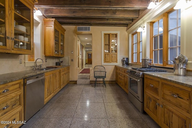 kitchen with beamed ceiling, dark stone countertops, sink, and stainless steel appliances