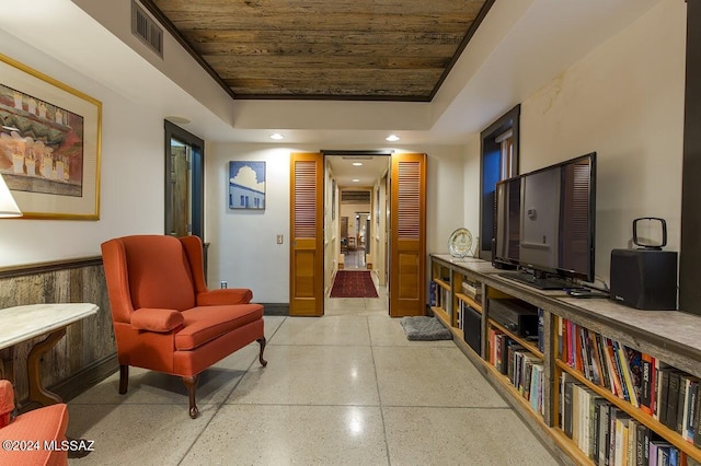 interior space featuring a tray ceiling, wood walls, and wooden ceiling