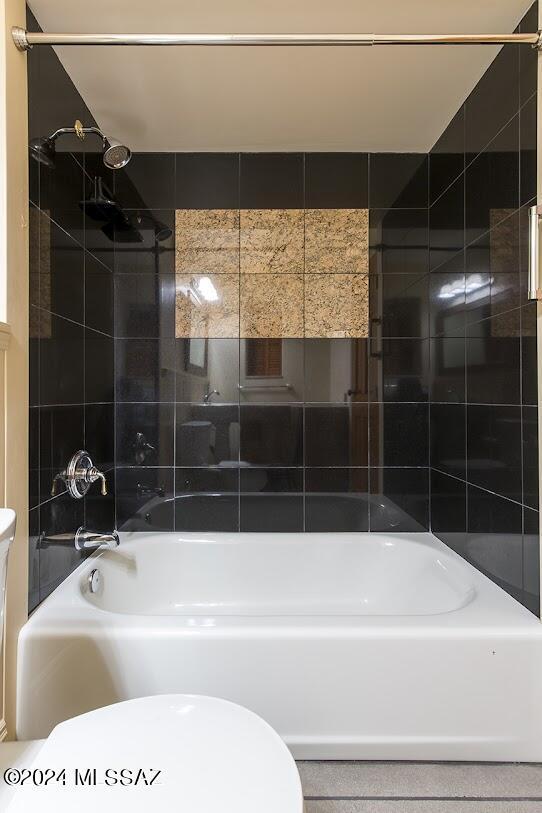 bathroom with tiled shower / bath combo and toilet