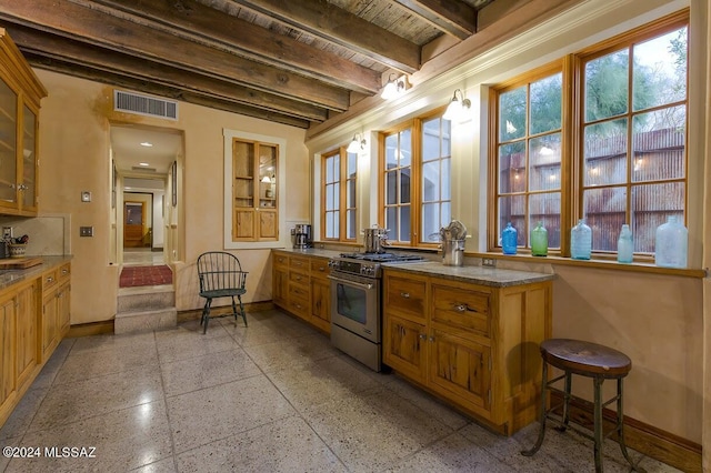 kitchen featuring beamed ceiling, a breakfast bar, and stainless steel range