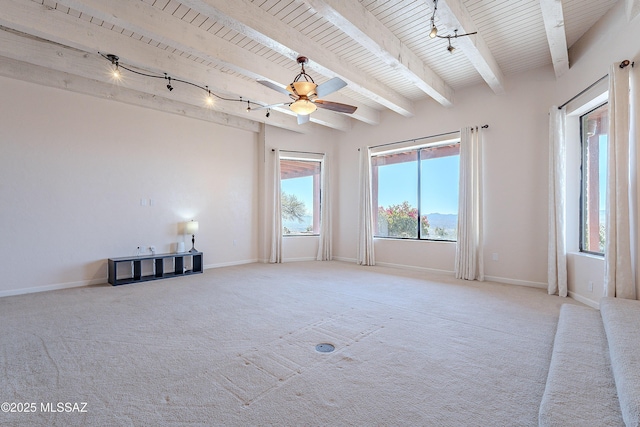 carpeted empty room with beam ceiling, ceiling fan, and track lighting