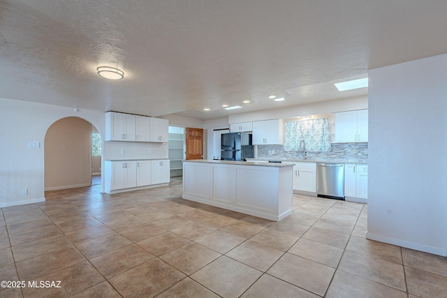 kitchen featuring black refrigerator, white cabinets, a kitchen island, and dishwasher