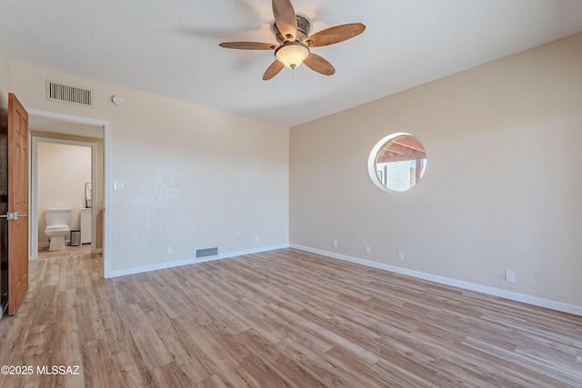 empty room with ceiling fan and light hardwood / wood-style flooring