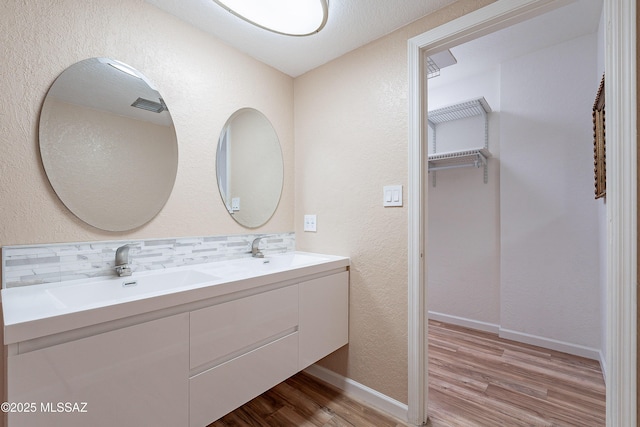 bathroom with hardwood / wood-style floors, vanity, and tasteful backsplash