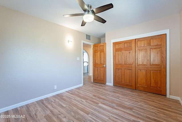 unfurnished bedroom with ceiling fan, light wood-type flooring, and a closet