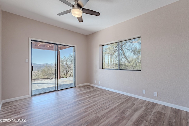 unfurnished room with ceiling fan, light hardwood / wood-style floors, and a mountain view