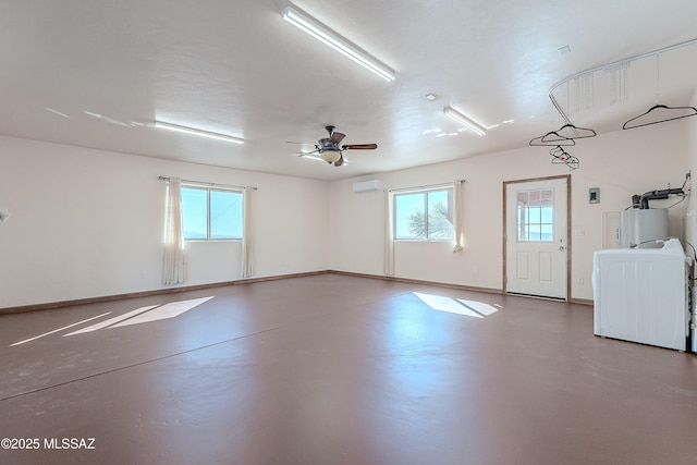 garage with a wall unit AC, washer / clothes dryer, ceiling fan, and water heater