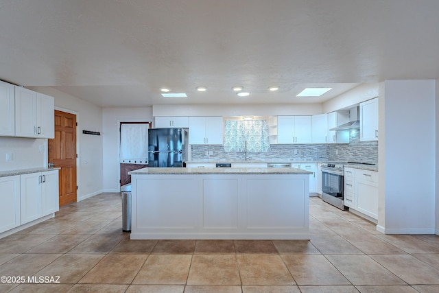 kitchen with wall chimney exhaust hood, stainless steel electric range, black refrigerator, and white cabinetry