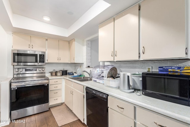 kitchen featuring dark hardwood / wood-style floors, sink, backsplash, black appliances, and a raised ceiling