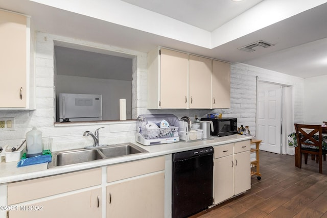 kitchen featuring sink, black appliances, dark hardwood / wood-style flooring, washer / dryer, and cream cabinetry