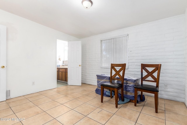 unfurnished dining area with brick wall and light tile patterned flooring