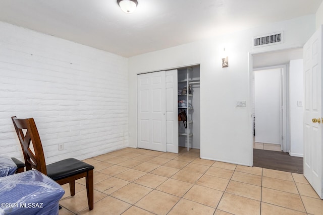 interior space with brick wall and light tile patterned floors